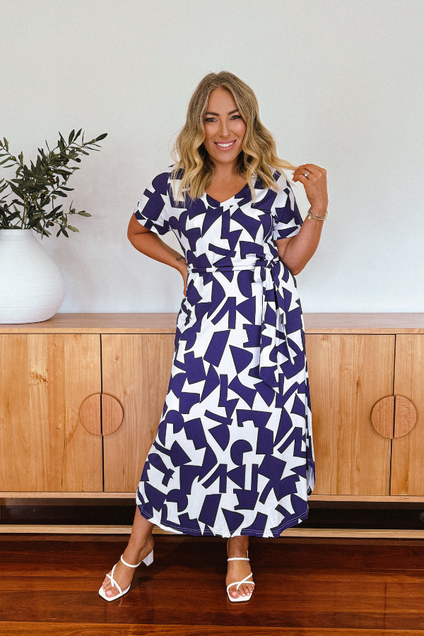 Woman standing in natural light wearing Bella Bamboo Tee Dress in navy abstract, styled with minimal accessories