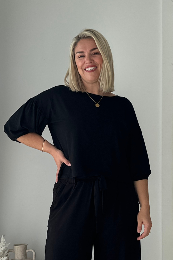 Woman posing in the Lexi Bamboo Top in black paired with Alexa Pants in black, hand on hip.