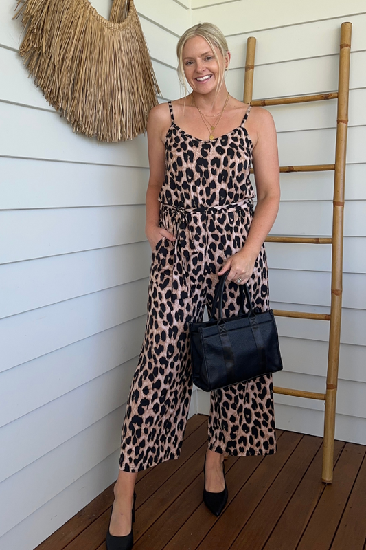 Full-length view of the Fay Bamboo Jumpsuit in Luxe Leopard styled with a handbag for a day-to-night look.