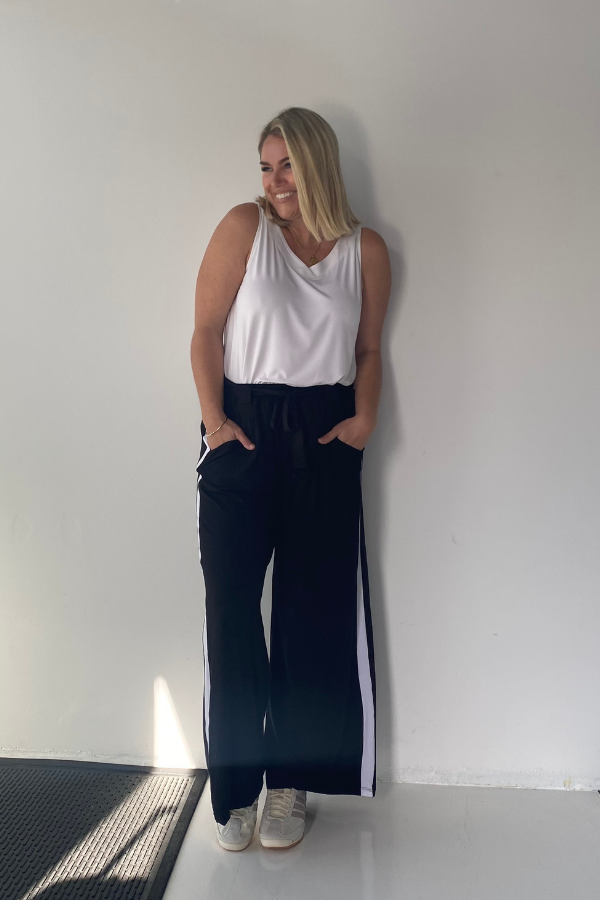 Model wearing Luna Bamboo Sleeveless Top in White with Alexa Pants in Black with a white stripe for a relaxed everyday look.