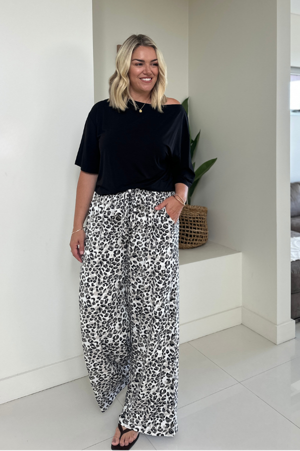 Woman wearing the Taylor Bamboo Top in Black paired with the Alexa Bamboo Pant in Leopard, front view with hand in pocket