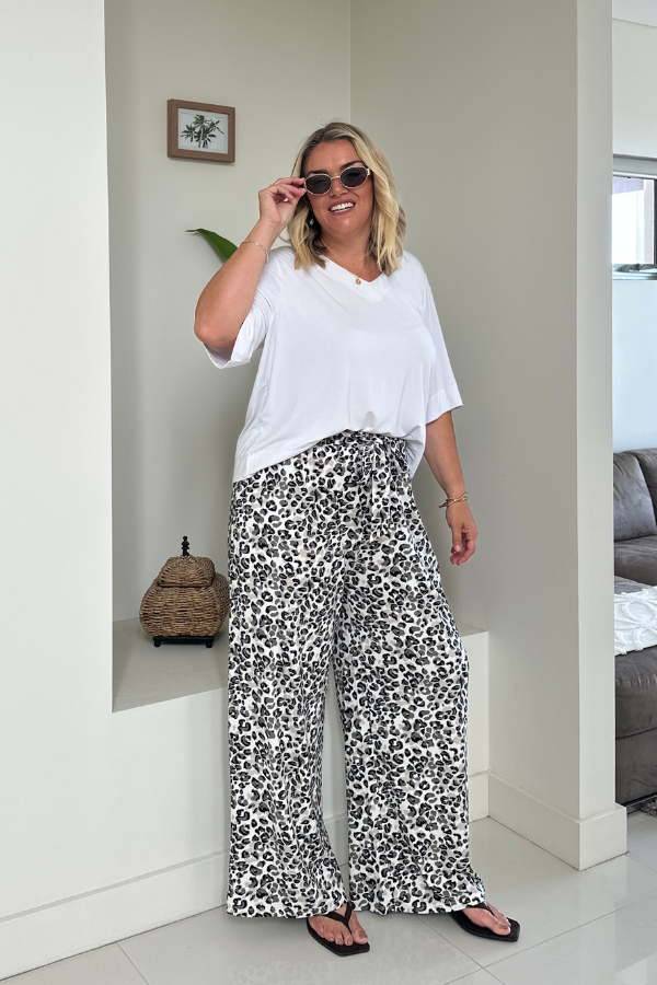 Woman wearing the Mara V-Neck Top in White paired with the Alexa Bamboo Pant in Leopard, front view