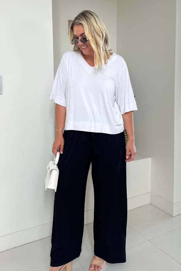 Woman wearing the Mara V-Neck Bamboo Top in White with the Alexa Pant in Black, full-length front view showing the relaxed fit