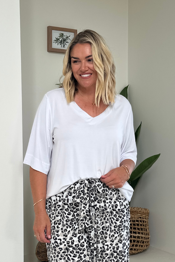 Woman wearing the Mara V-Neck Bamboo Top in White with the Alexa Pant in Leopard print, front view showing the V-neckline