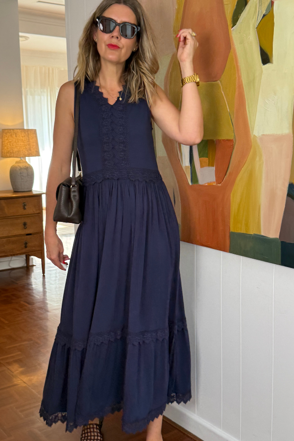Model wearing Natali The Label's Evangeline Bamboo Dress in navy—featuring a sleeveless V-neckline, tiered lace maxi skirt.